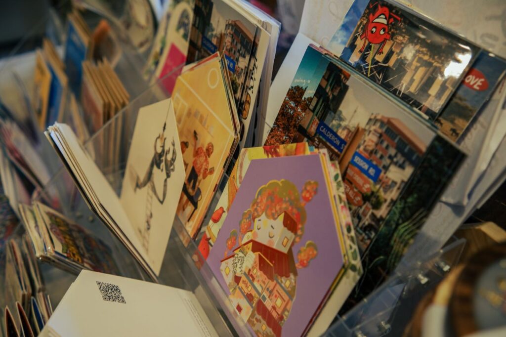A colorful assortment of postcards featuring art and scenic views displayed on a rack.
